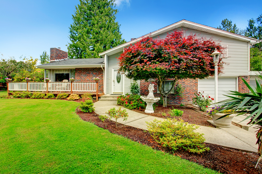 House exterior with brick wall trim walkout deck and beautiful front yard landscape