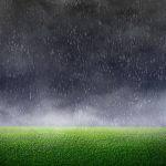 dark sky on a green lawn with rain coming down