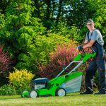 man mowing lawn with green lawn mower