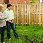 couple looking at the spotty growth of their yard.