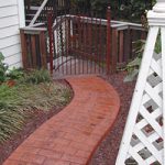 Red brick pathway leading up to red gate in garden