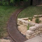 Black stone path leading to wooden gate from driveway